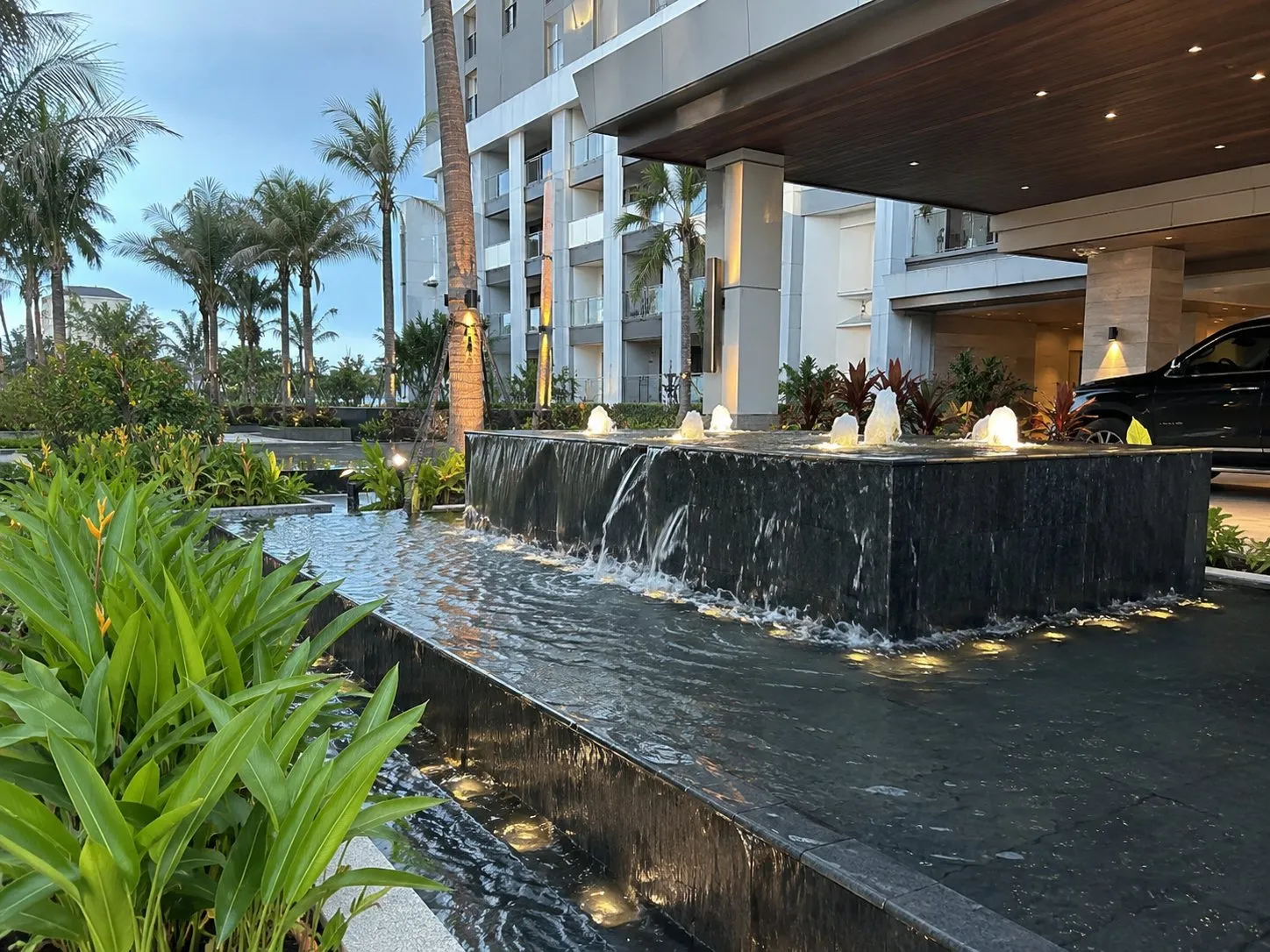 Lit weir and bubbler water feature at a resort arrival court