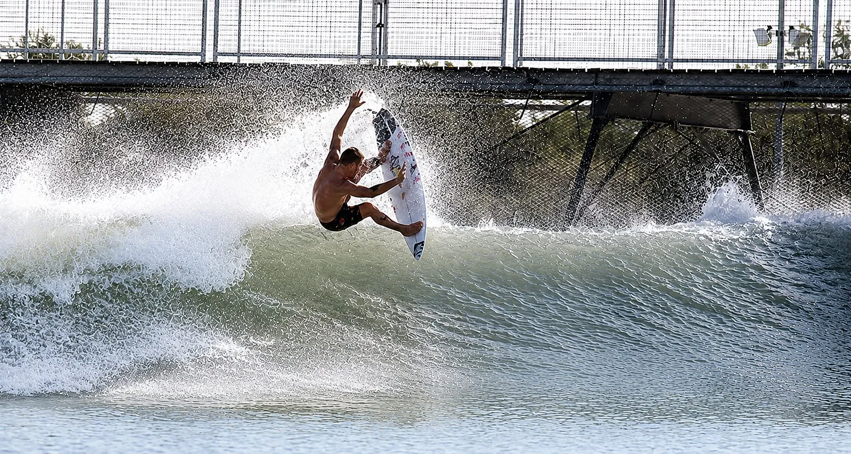 Surfer going airborne off the lip of a machine-generated wave in a surf lagoon